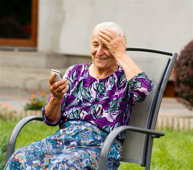 Funny grandmother confused with using smartphone, stock photo