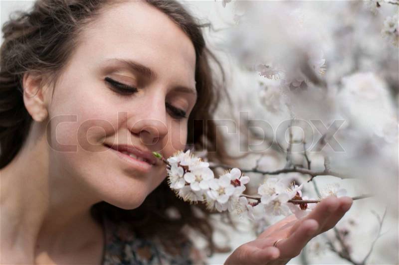 Sensual portrait of a spring woman, beautiful face, female enjoying cherry blossom, dreamy girl with pink fresh flowers outdoor, seasonal nature, tree branch and natural beauty, stock photo
