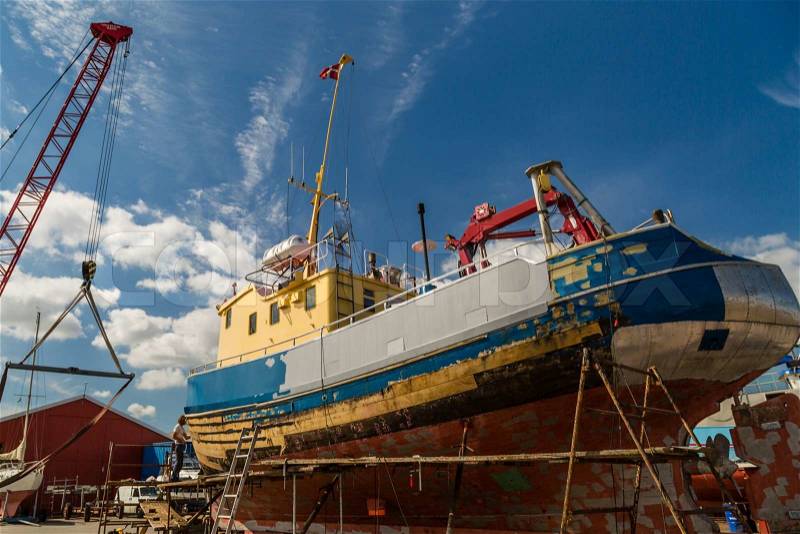Medium-sized boat undergoing maintenance and repairs while in dock, stock photo