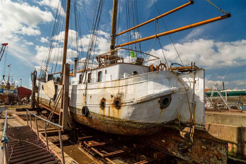 Large old sailing boat undergoing serious repair work while docked on the quay, stock photo