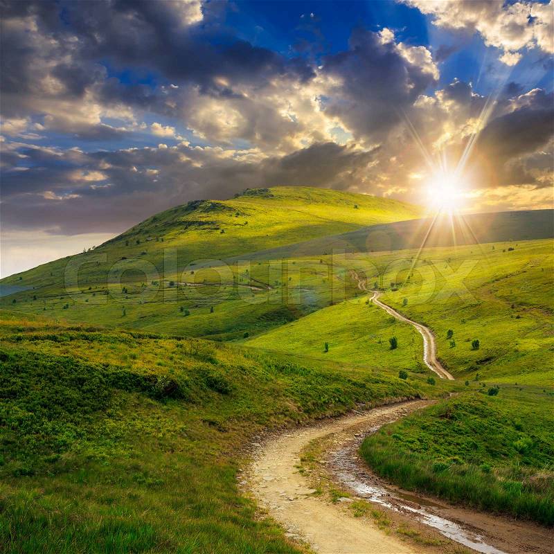 Summer landscape. mountain path through the field turns uphill to the sky at sunset, stock photo