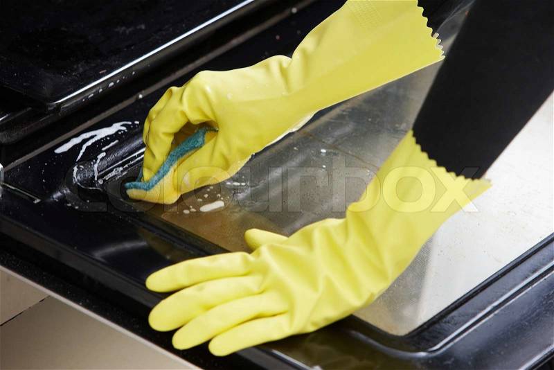 Hands with yellow rubber gloves cleaning the oven, stock photo