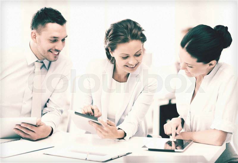 Smiling business team working with tablet pcs in office, stock photo