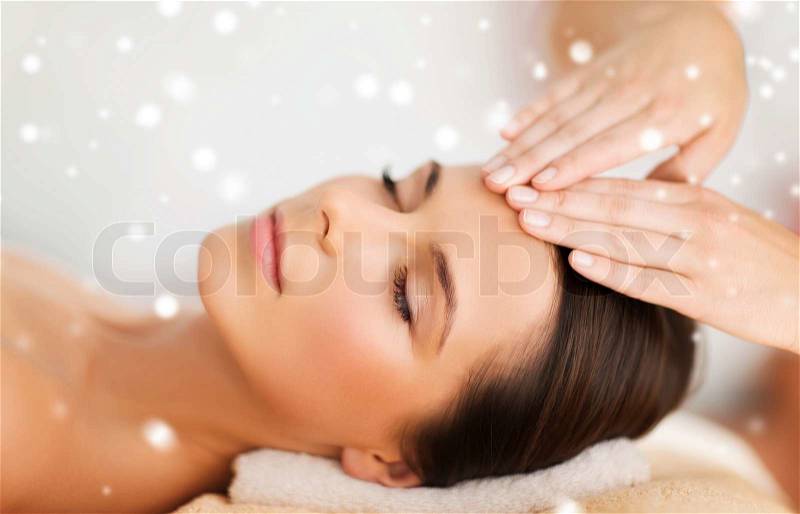 Beauty, health, holidays, people and spa concept - beautiful woman in spa salon getting face or head massage, stock photo