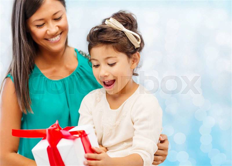 Christmas, holidays, celebration, family and people concept - happy mother and girl with gift box over blue lights background, stock photo