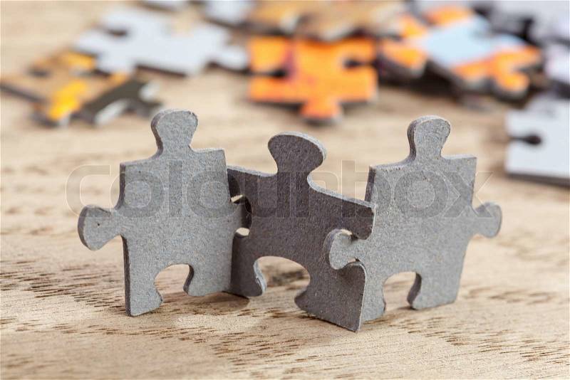 Concept of teamwork: Three jigsaw puzzle pieces on a table joint together. Shallow depth of field, stock photo