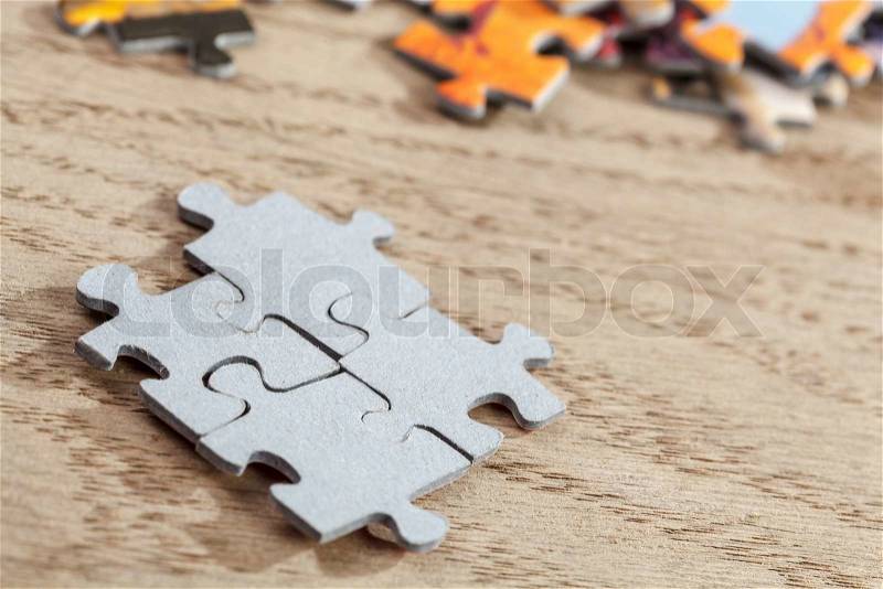 Closeup of four connected jigsaw puzzle pieces on a table. Shallow depth of field, stock photo