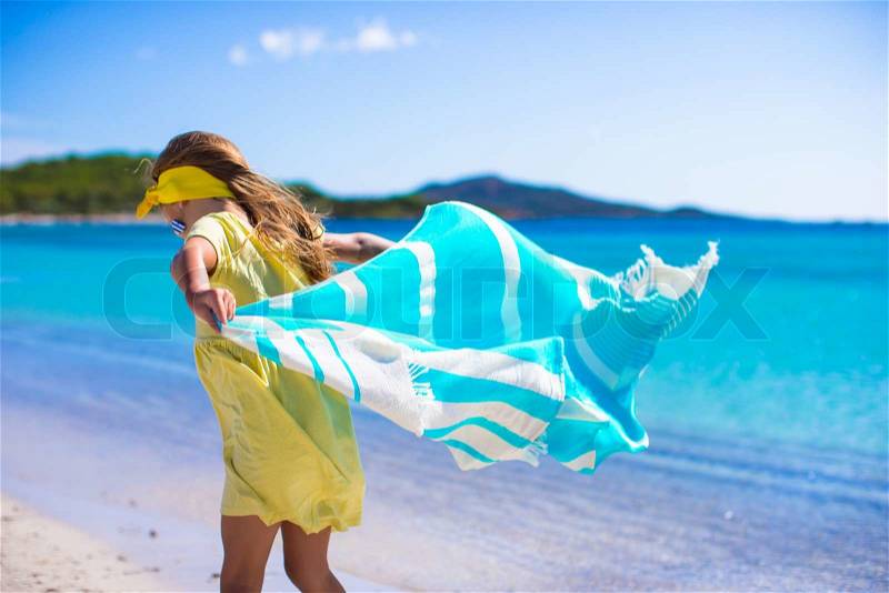 Little girl have fun with beach towel during tropical vacation, stock photo