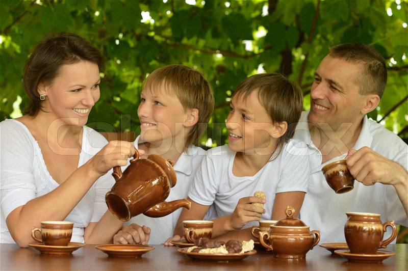 Happy family drinking tea in the garden in summer, stock photo