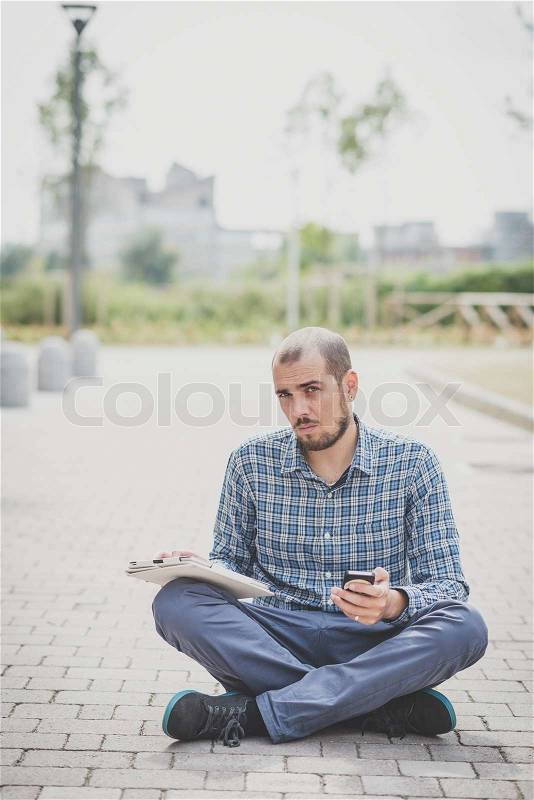 Handsome hipster casual multitasking modern man using tablet in the city, stock photo