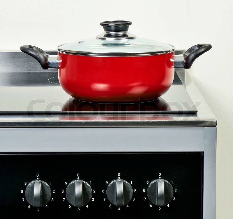 Red ceramic pan with cover on Electric hob in modern and domestic kitchen, stock photo
