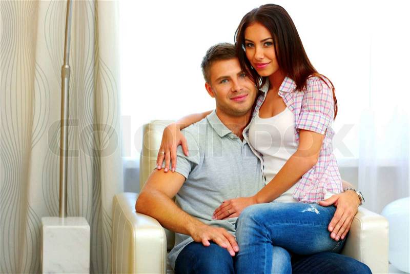 Portrait of a young happy couple sitting on the sofa together, stock photo
