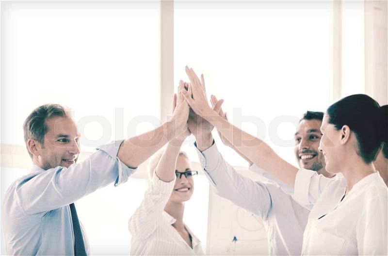 Success and winning concept - happy business team giving high five in office, stock photo