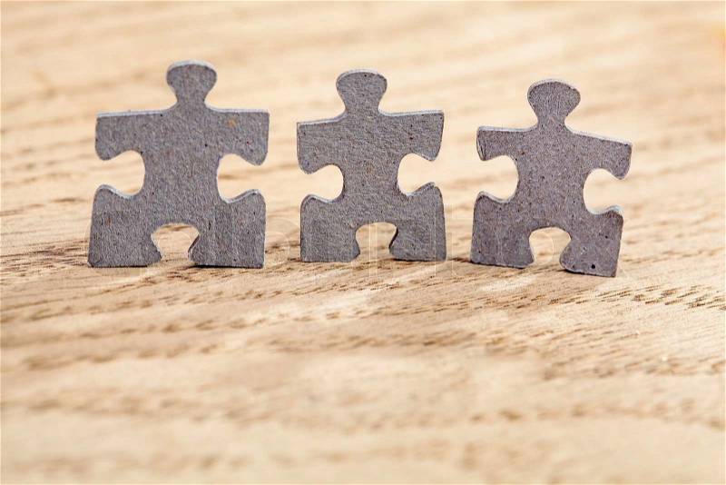 Concept of teamwork: Three jigsaw puzzle pieces on a table. Shallow depth of field, stock photo