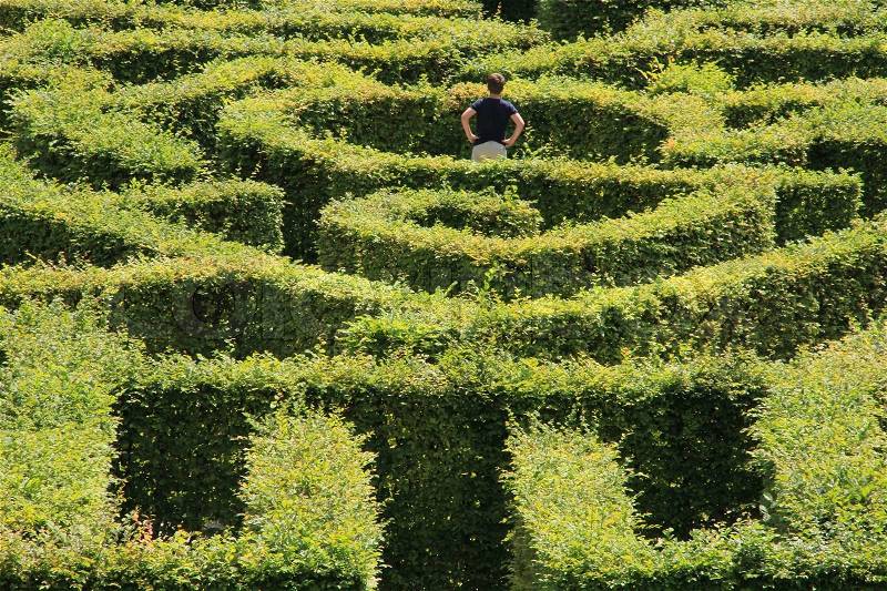 The game, labyrinth, the boy with his hands on the hips is thinking....which way?, stock photo