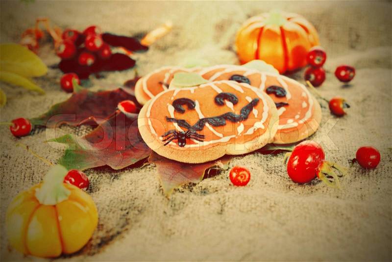 Closeup of Halloween decor pumpkin cookies and assorted pumpkins. Popular American event party decorative dessert idea, stock photo