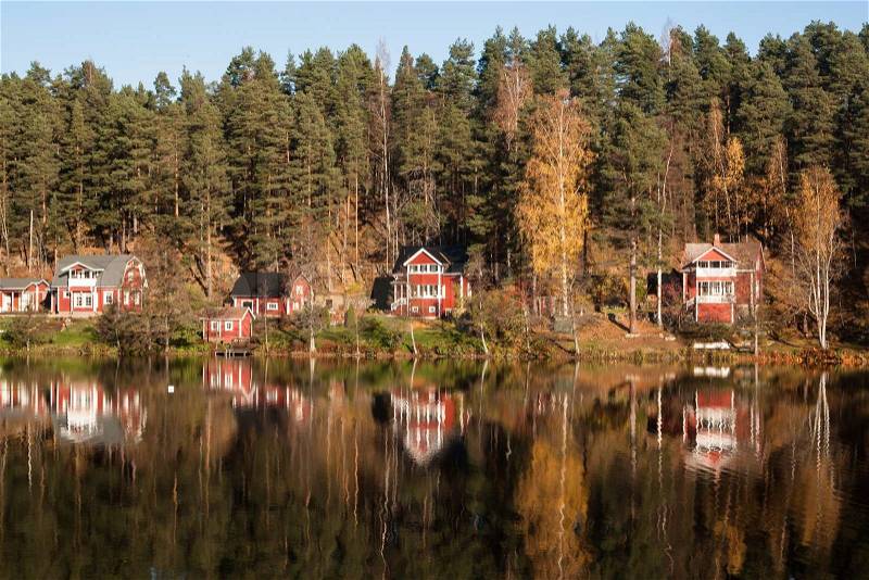 Red summer cottages by an autumn lake, stock photo
