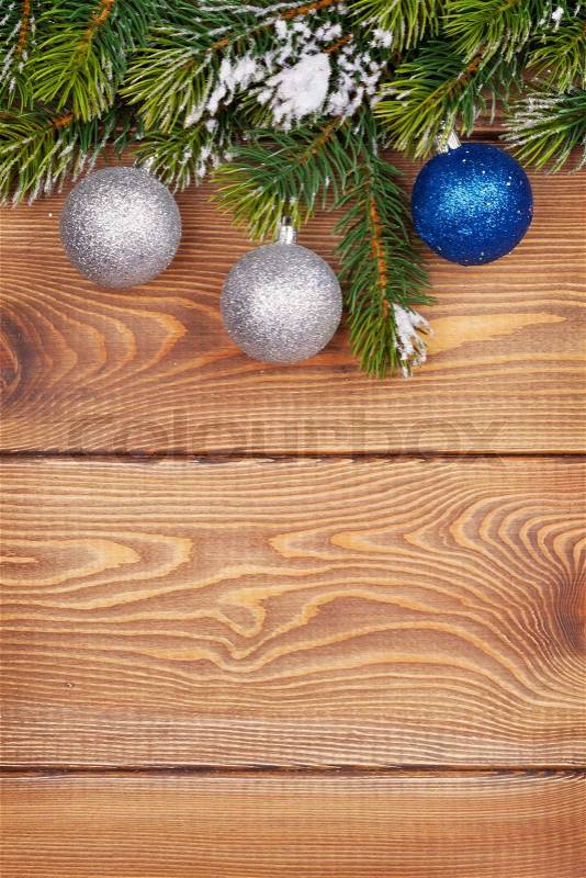 Christmas fir tree with snow and baubles on rustic wooden board with copy space, stock photo