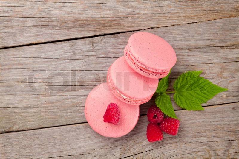 Pink raspberry macaron cookies on wooden table background, stock photo