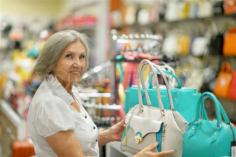 Smiling old lady choosing dress in store, stock photo