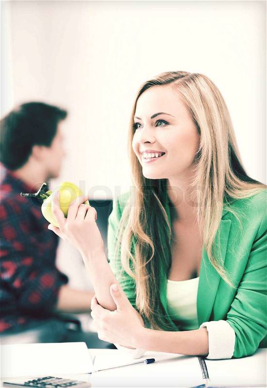 Education concept - smiling student girl with green apple in college, stock photo
