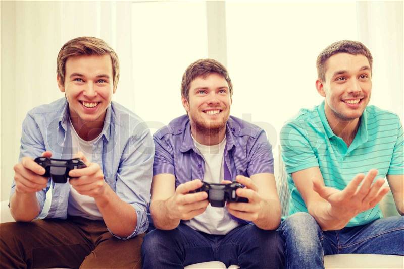 Friendship, technology, games and home concept - smiling male friends playing video games at home, stock photo