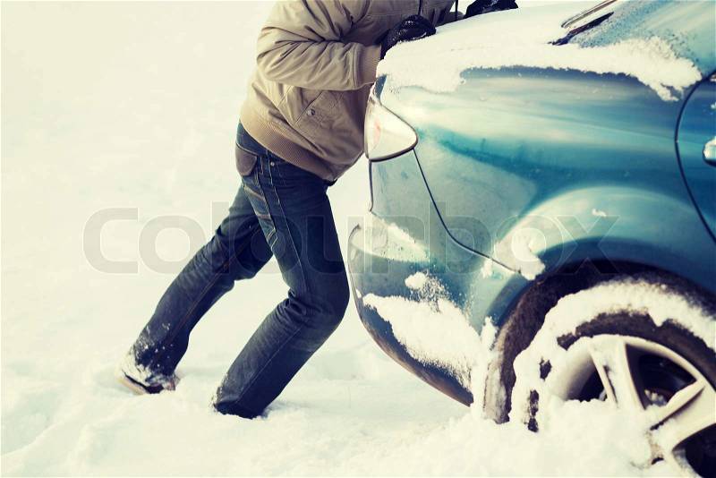 Transportation, winter and vehicle concept - closeup of man pushing car stuck in snow, stock photo