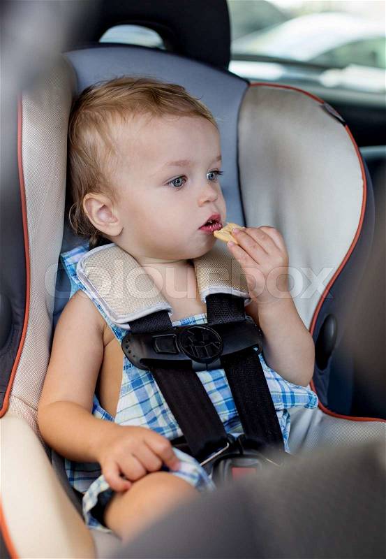 Happy Toddler boy in the car eating cookies, stock photo