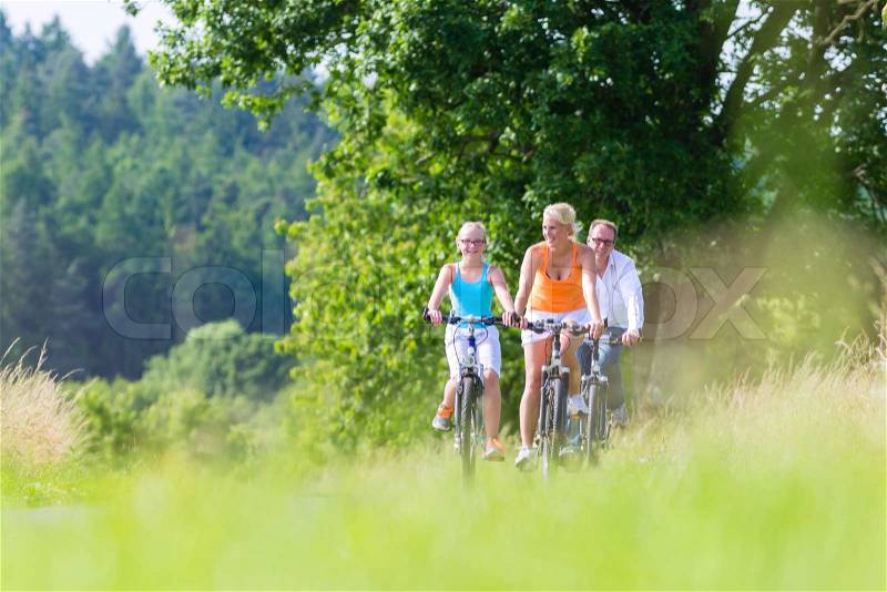 Parents and daughter have bicycle or bike tour on country lane, stock photo