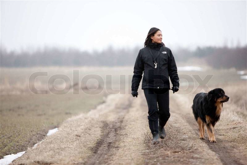 A pregnant woman and her pet dog taking a walk in the field, stock photo