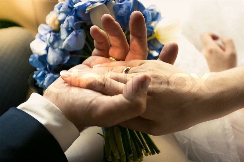Closeup photo of groom holding brides hand in car, stock photo