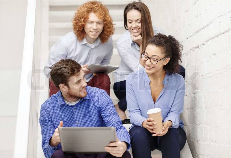 Business, technology and startup concept - smiling creative team with laptop and tablet pc computer sitting on staircase, stock photo