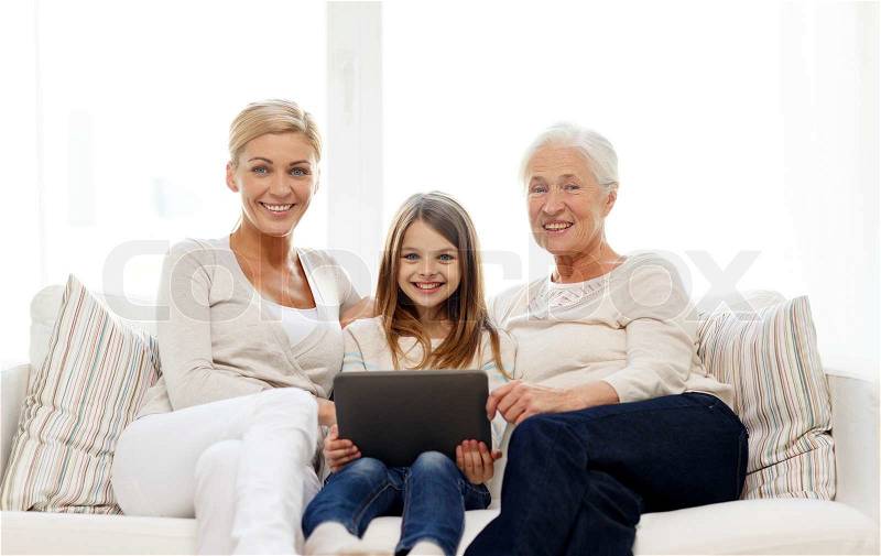 Family, generation, technology and people concept - smiling mother, daughter and grandmother with tablet pc computer sitting on couch at home, stock photo