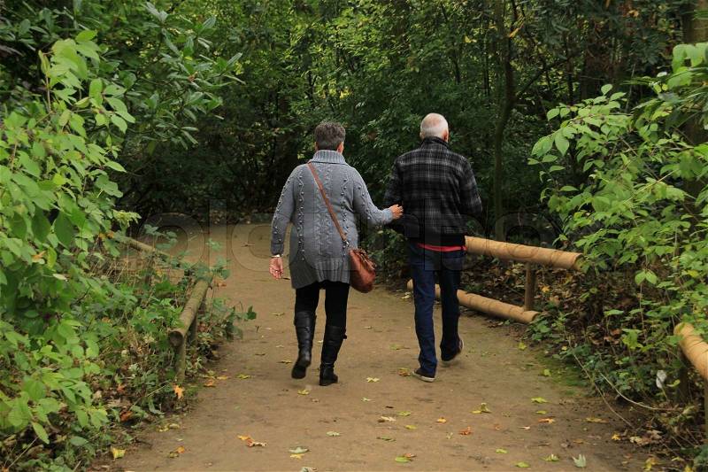 The elderly couple, man and wife, walk in the forest and having fun in autumn, stock photo