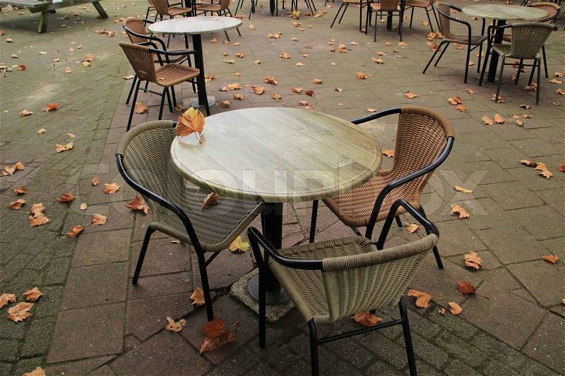 Fallen leaves, a table and chairs waiting for people in autumn, stock photo