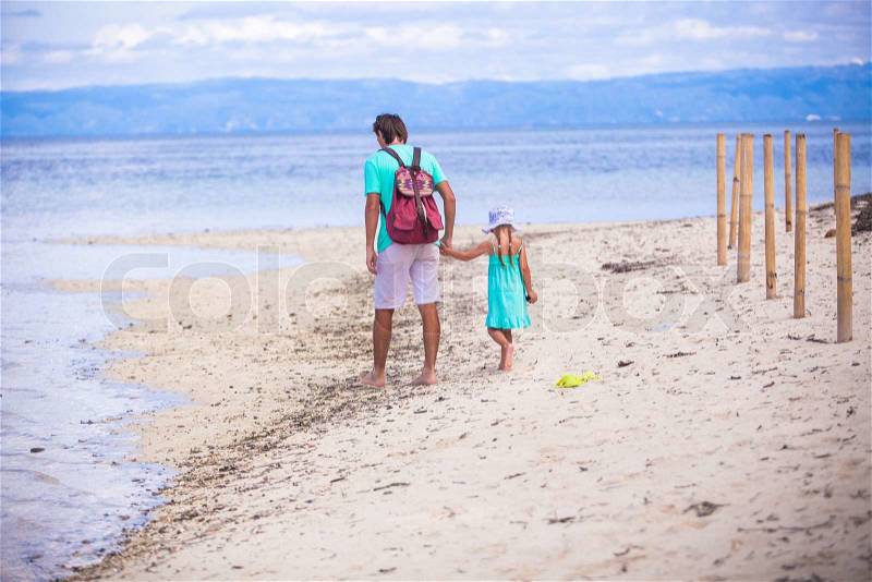 Back view of young father and his little girl walking by the sea, stock photo