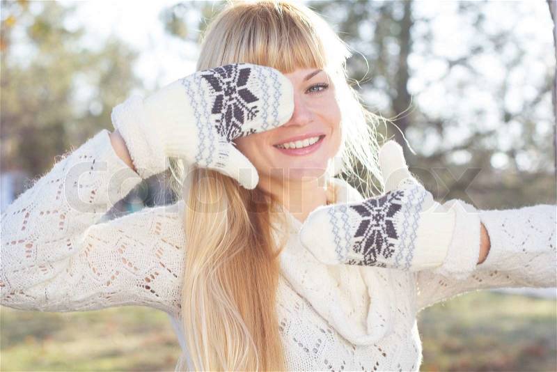 Attractive blonde smiling girl with is wearing mittens,knitted dress posing outdoors, stock photo