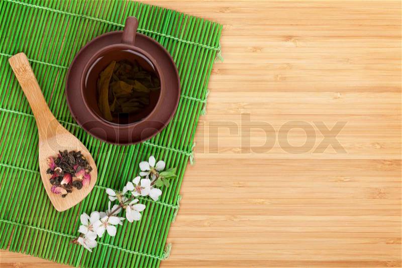 Japanese green tea and sakura branch over mat and bamboo table with copy space, stock photo