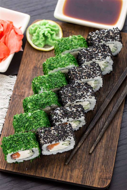Salmon sushi roll covered with dill and sesame, stock photo