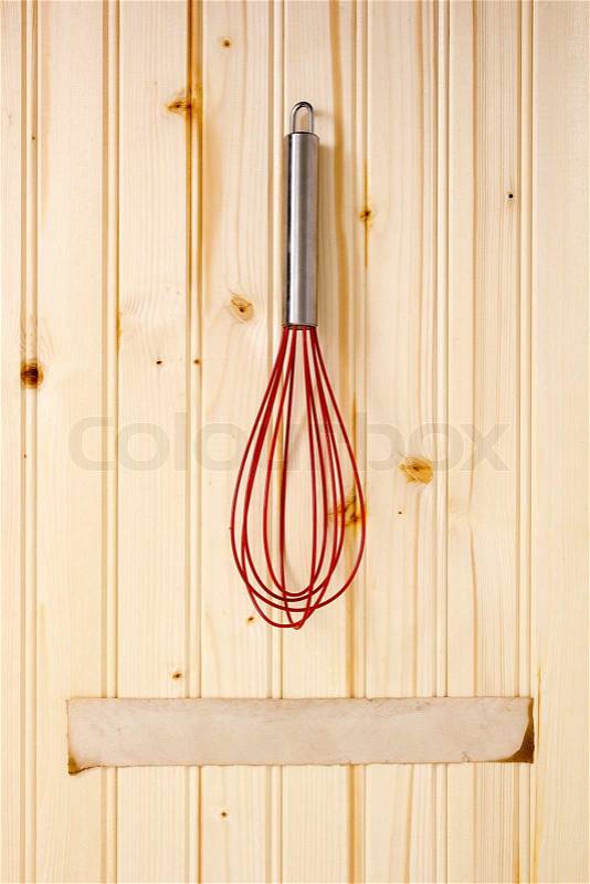Beater for mixing ingredients in cooking on a wooden wall, stock photo