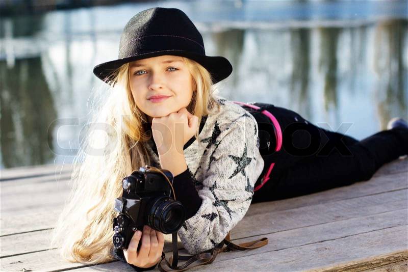 Little girl photographer outdoors with camera in winter cold day near lake. Portrait caucasian female blonde child model outside, stock photo
