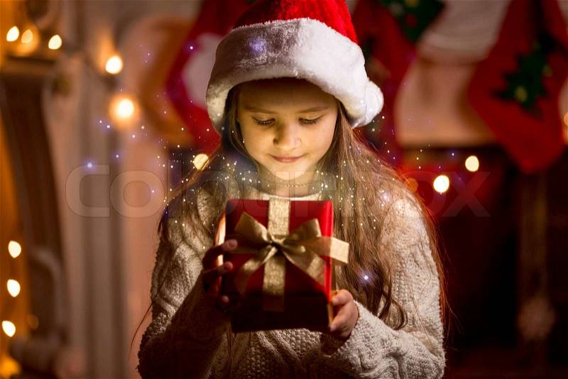 Little cute girl looking inside of glowing Christmas present box, stock photo