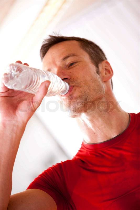 A male caucasian athlete drinking bottled water, stock photo