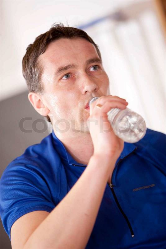 A thirsty male caucasian athlete drinking bottled water, stock photo