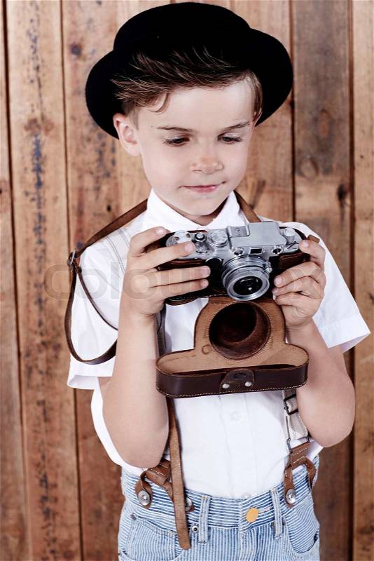 Young boy looking at old camera\, stock photo