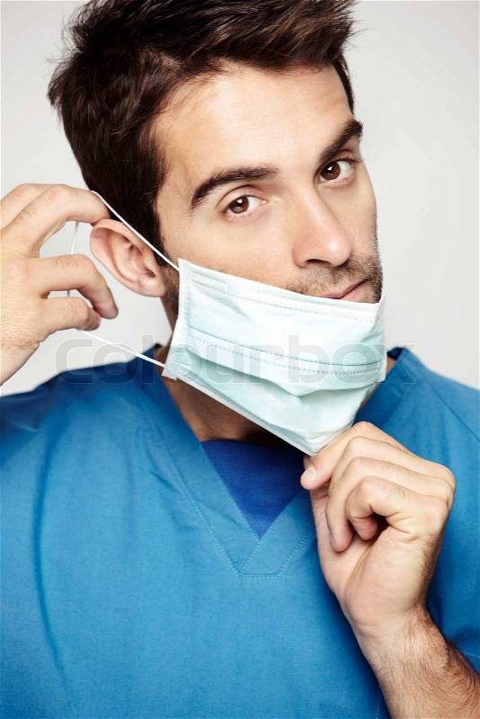 Male surgeon takes on his mask, stock photo