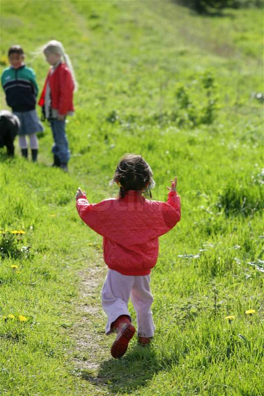 Small girl running in a green field in spring, stock photo