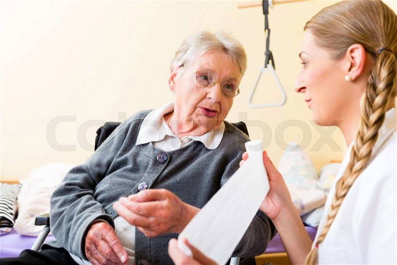 Nurse taking care of senior woman in retirement home bandaging a wound, stock photo