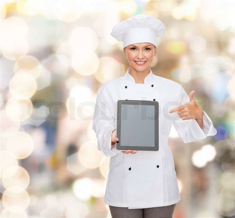 Cooking, holidays, technology and food concept - smiling female chef, cook or baker with tablet pc computer pointing finger to blank screen over lights background, stock photo