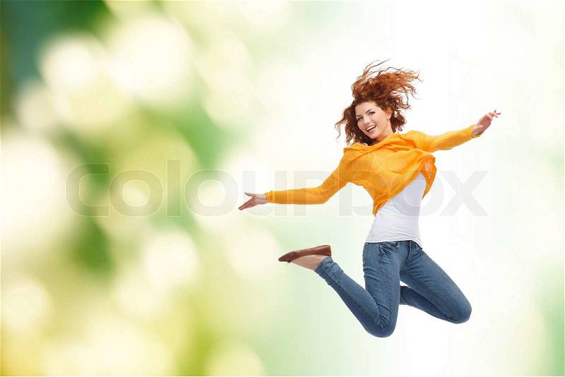 Happiness, freedom, movement and people concept - smiling young woman jumping high in air over green background, stock photo